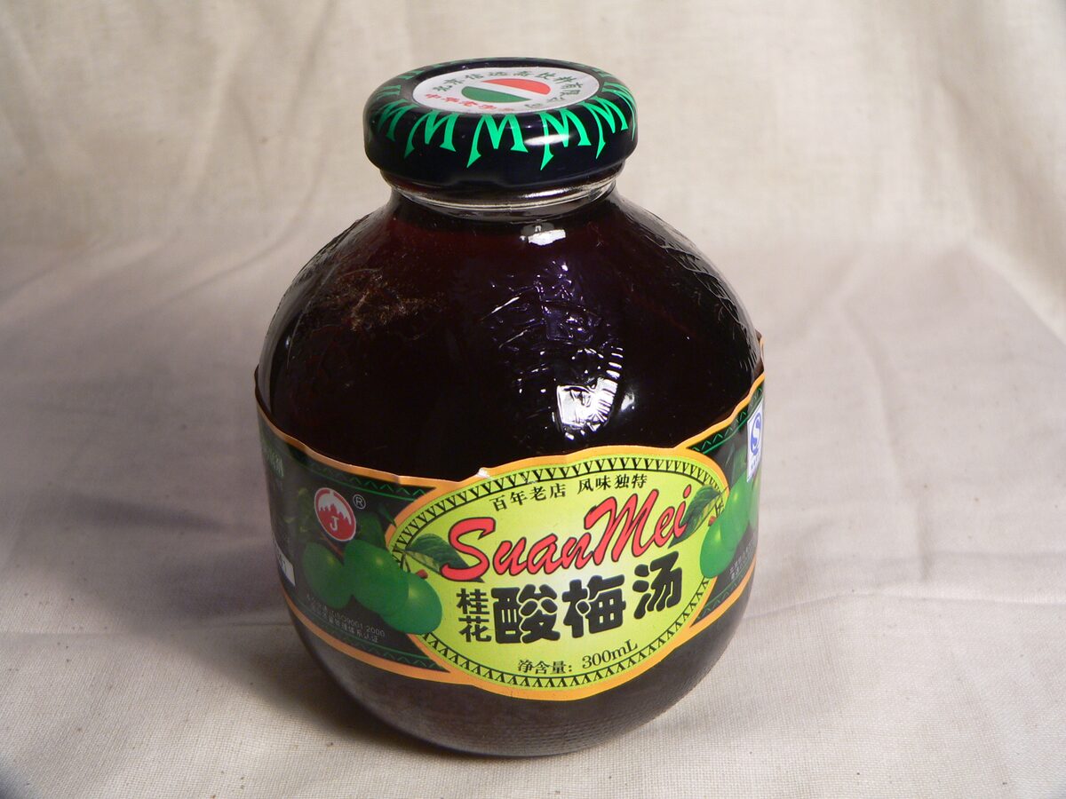 A round glass bottle of commercial suanmeitang, the dark sweet-sour smoked plum drink, with its label