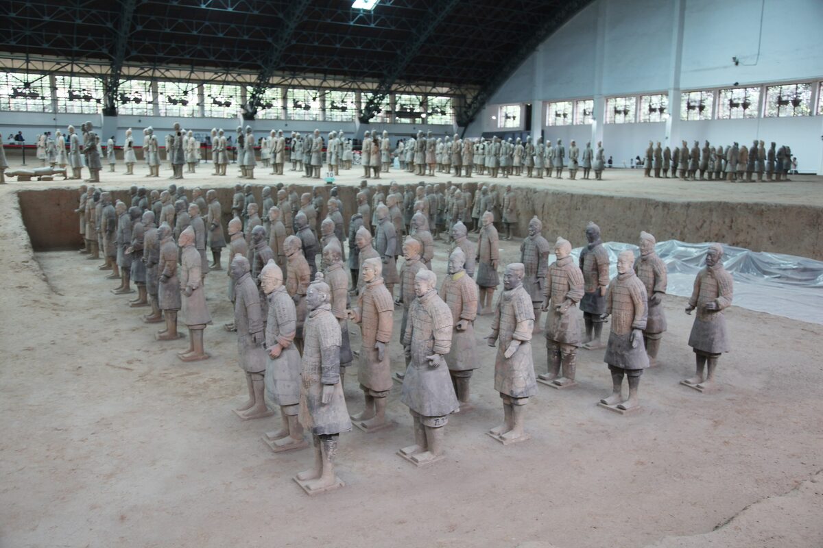 Ranks of clay warriors standing in a trench in Pit 1 of the Terracotta Army, with more figures lined up beyond the hangar