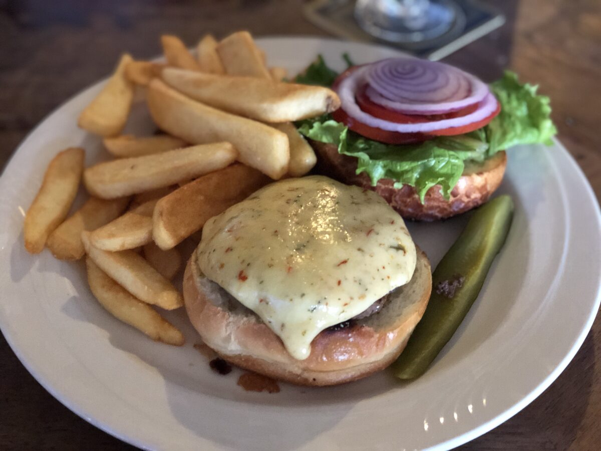 A cheeseburger with pickle and fries on a white plate