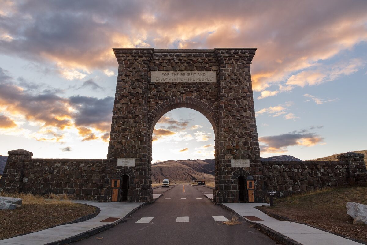 Roosevelt Arch in Gardiner under a colorful sunrise sky