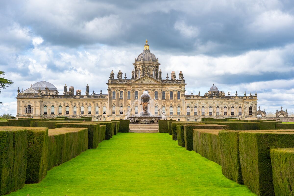Castle Howard, a grand baroque palace with a dome, seen across a lake and lawns