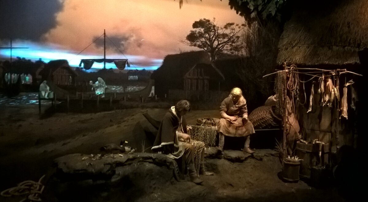 A reconstructed Viking-age street scene with a wooden house and a figure at work inside Jorvik Viking Centre