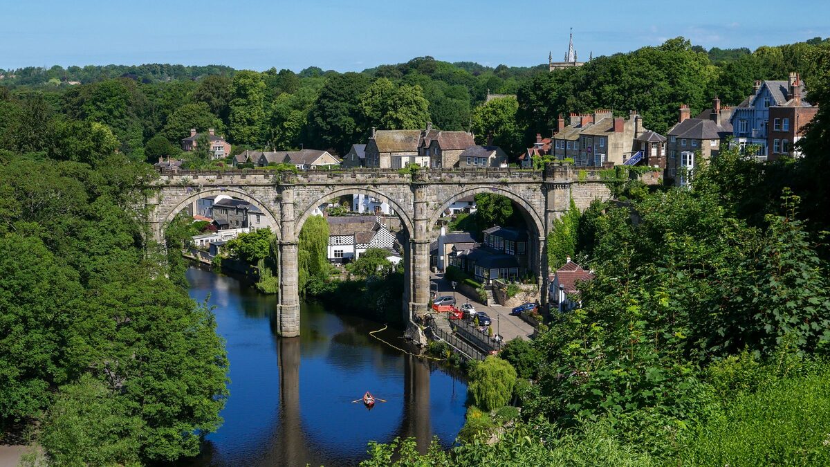 The stone railway viaduct over the River Nidd in Knaresborough, with houses on the wooded gorge