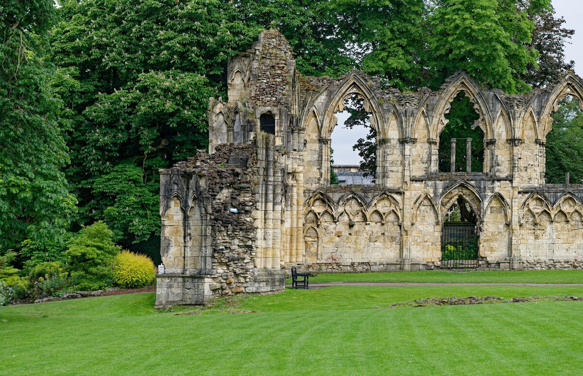 The ruined Gothic arches of St Mary's Abbey standing on a green lawn in the Museum Gardens in York
