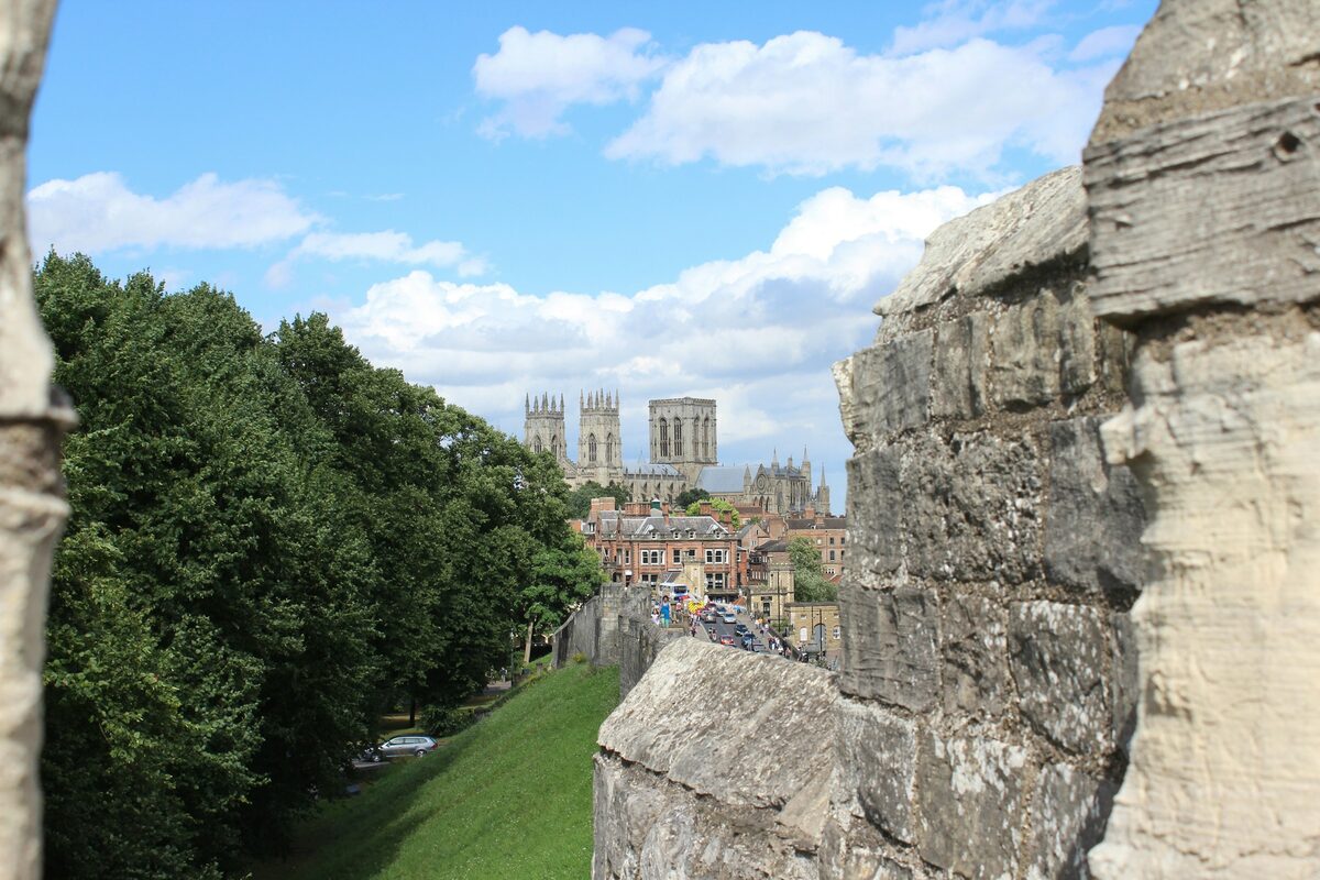 A stretch of York's medieval city walls with a narrow walkway on top, and the towers of York Minster rising behind