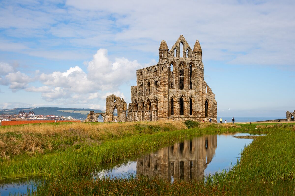 The ruined Gothic arches of Whitby Abbey on a clifftop under a cloudy sky