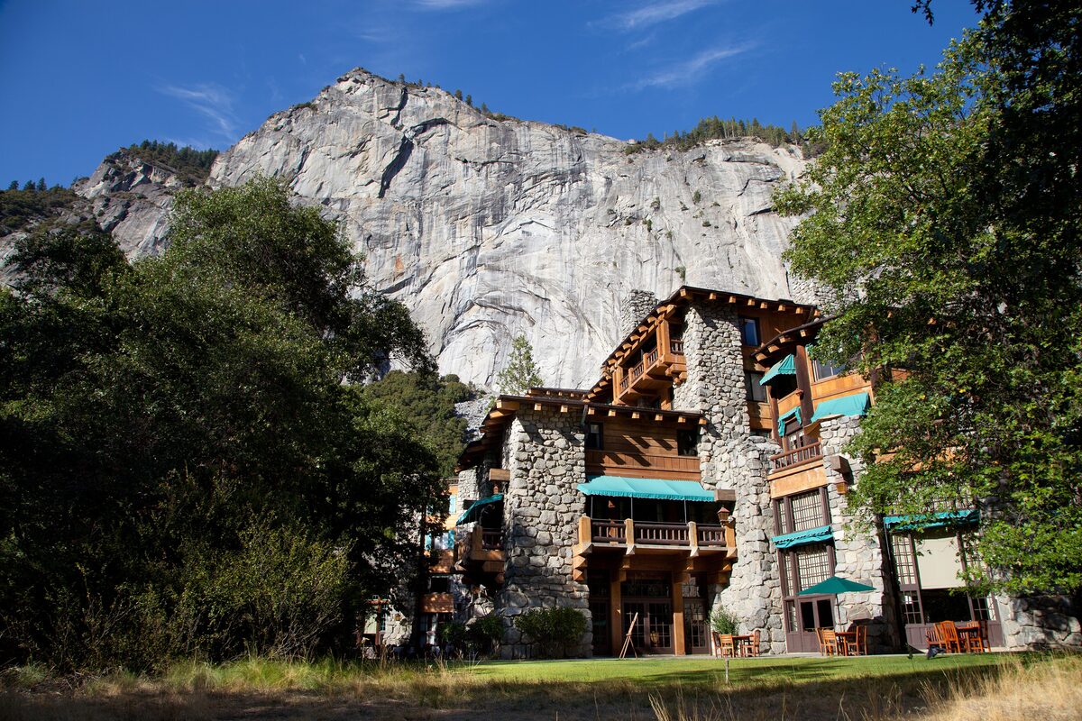 The stone-and-timber Ahwahnee hotel beneath a sunlit granite cliff