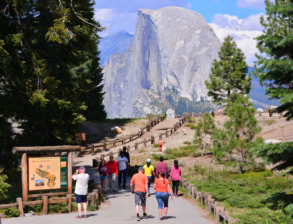 Visitors walking the Glacier Point path toward a Half Dome view