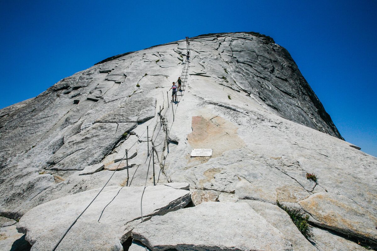 Hikers climbing the Half Dome cables up the bare granite slope