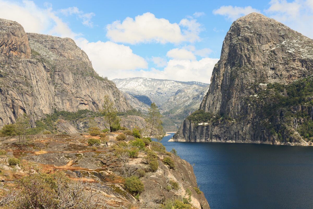 Hetch Hetchy Reservoir between granite cliffs under a blue sky