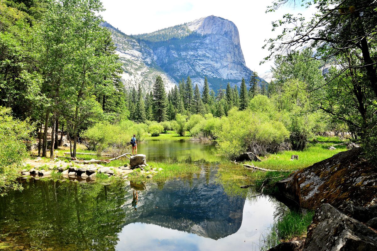 Mirror Lake's green shore and a granite peak reflected in still water