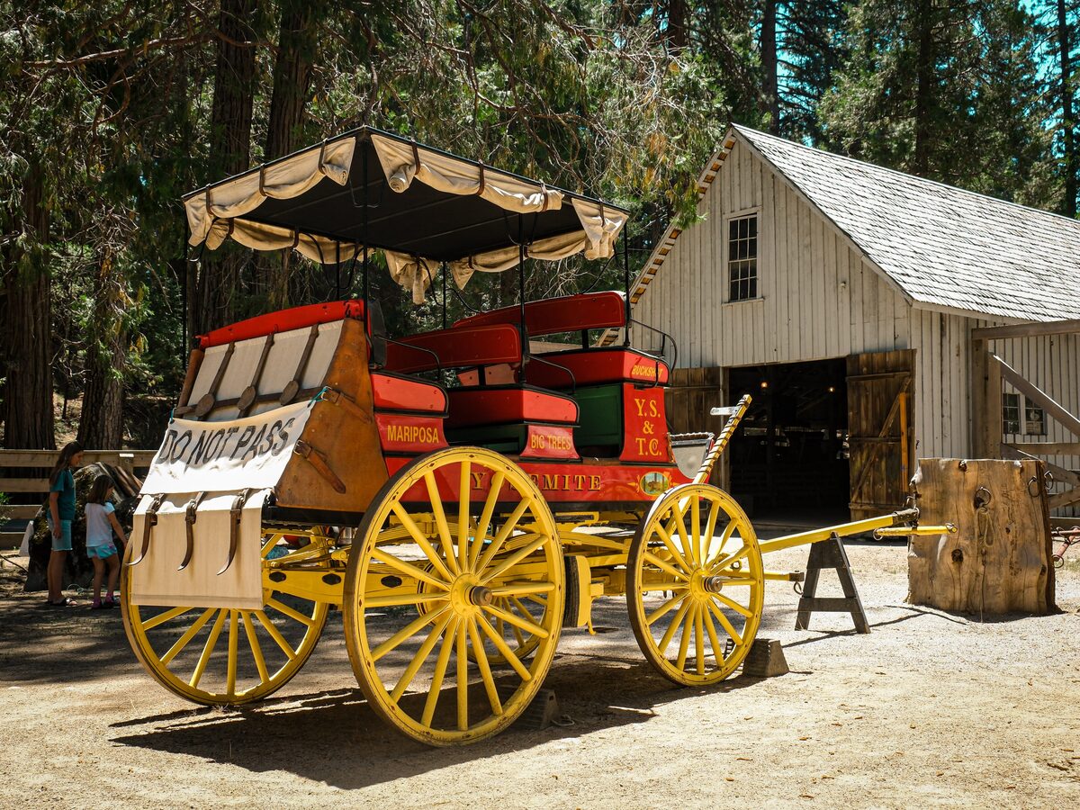 A red and yellow Yosemite Stage and Turnpike stagecoach beside a barn