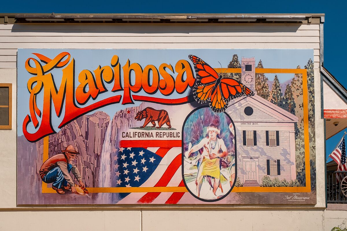A colorful Mariposa mural with a monarch butterfly and the old courthouse