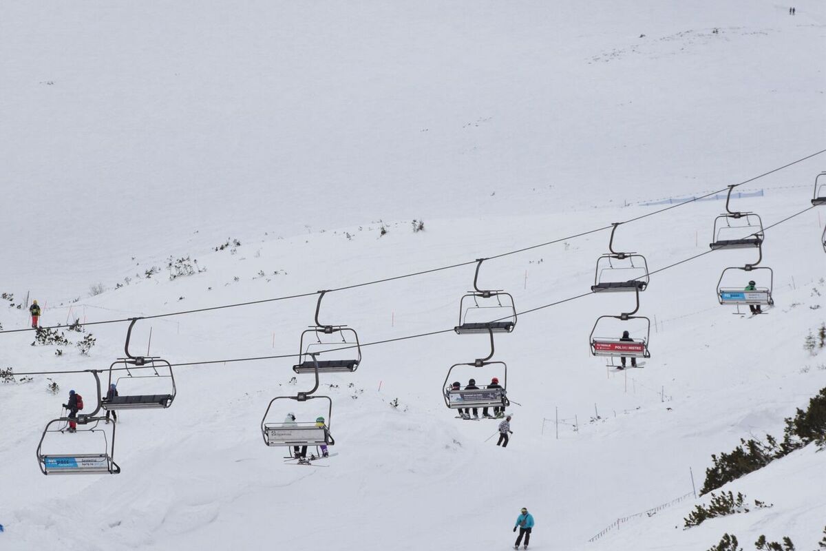 A chairlift carrying skiers over an open, snowy bowl dotted with dwarf pines, in the Tatras above Zakopane