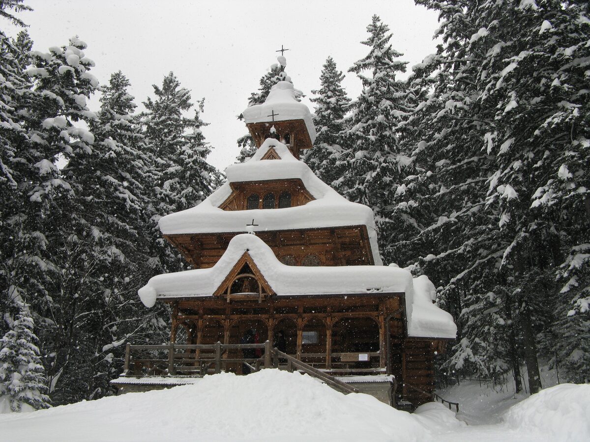 The wooden Jaszczurówka chapel under heavy snow, with snow-laden spruces around it