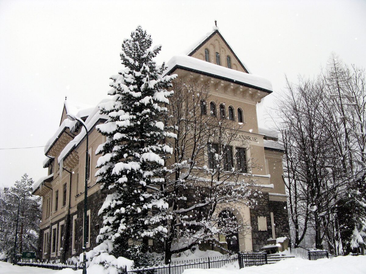 The Tatra Museum building in snow, with a snow-laden spruce in front of its stone entrance