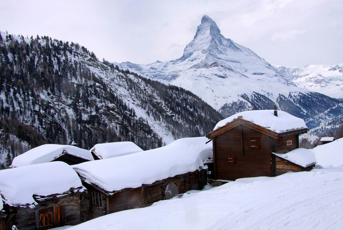 Snow-covered wooden barns of Findeln with the Matterhorn rising behind them