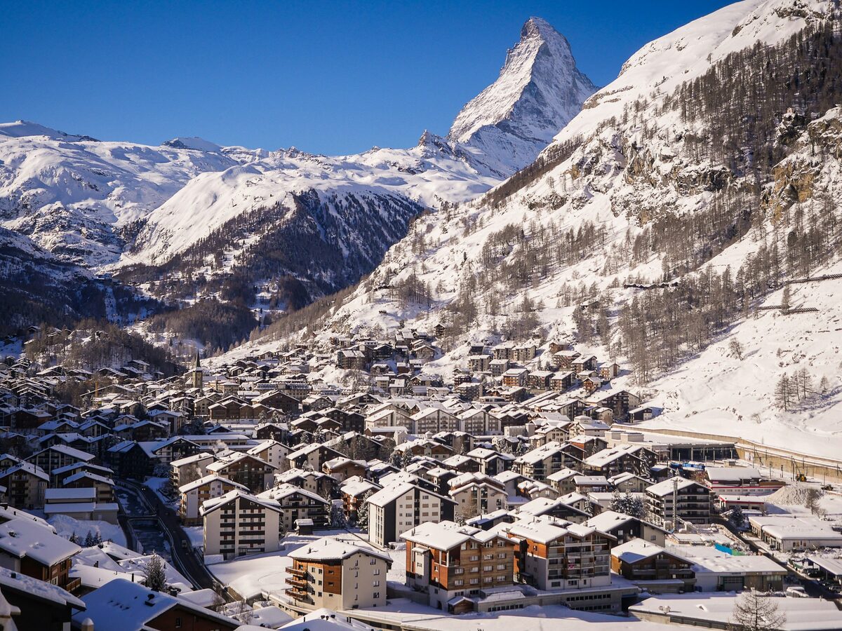 Snow-covered chalet roofs of Zermatt seen from above, with the Matterhorn rising behind