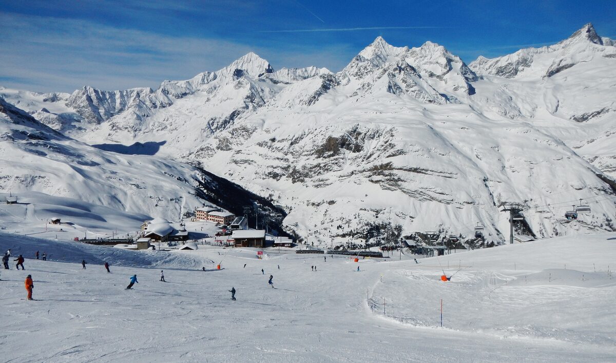 Skiers on the wide piste between Gornergrat and Riffelberg, with the buildings far below