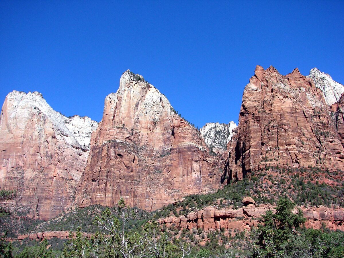 The three Patriarchs, red and white sandstone peaks under blue sky