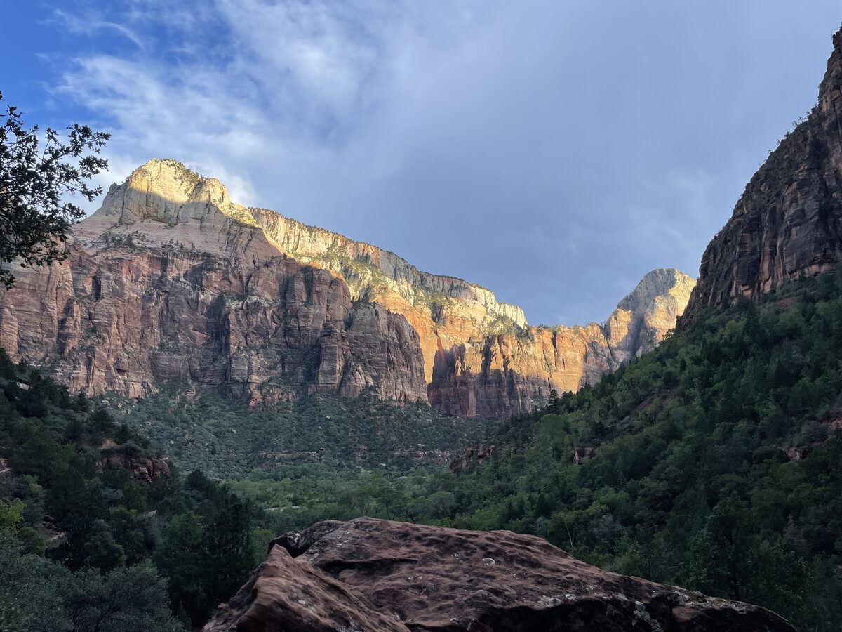 Sunlit cliffs above the forested canyon seen from the Emerald Pools trail