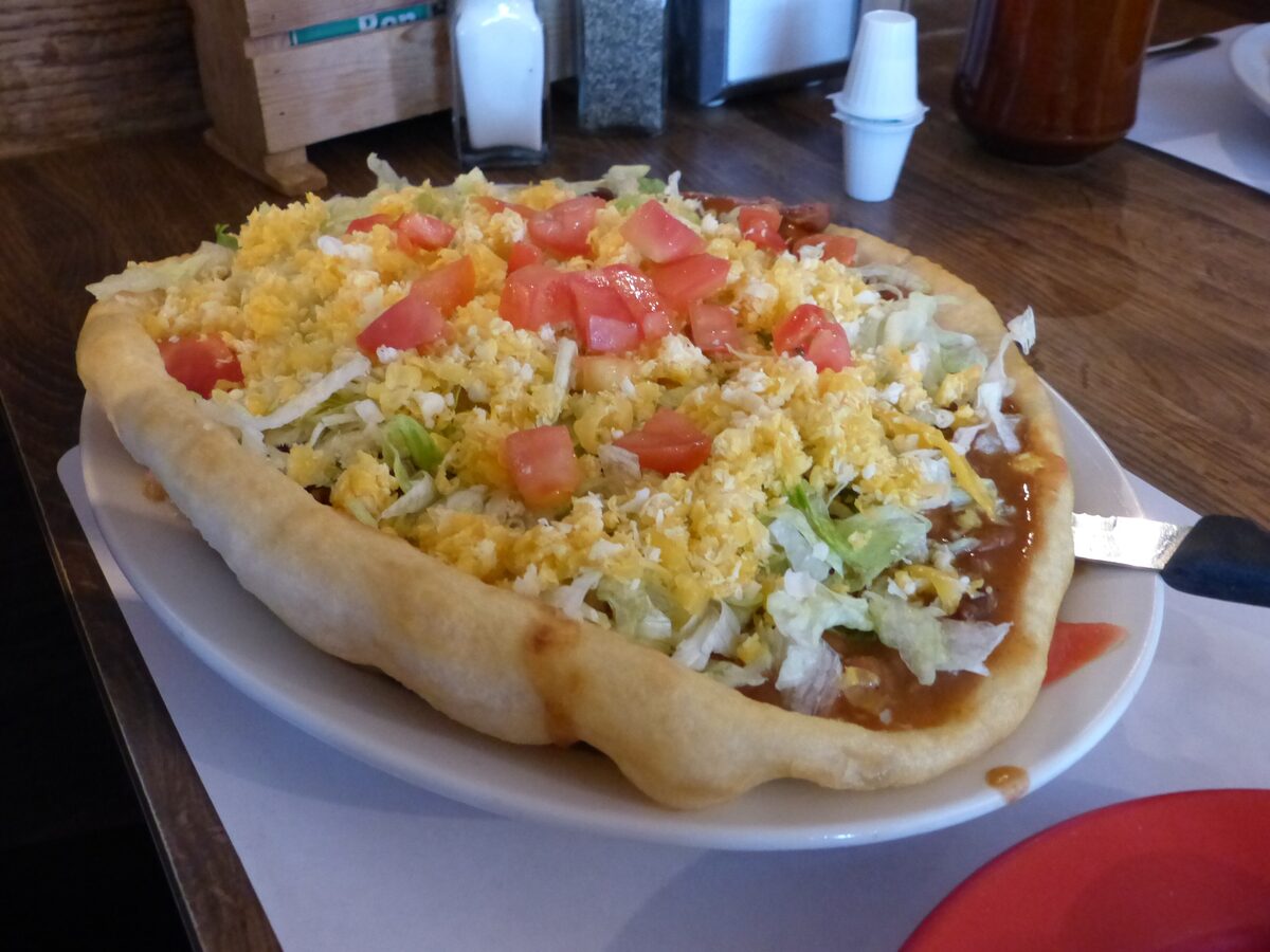 A Navajo taco, frybread topped with beans, cheese, lettuce and tomato