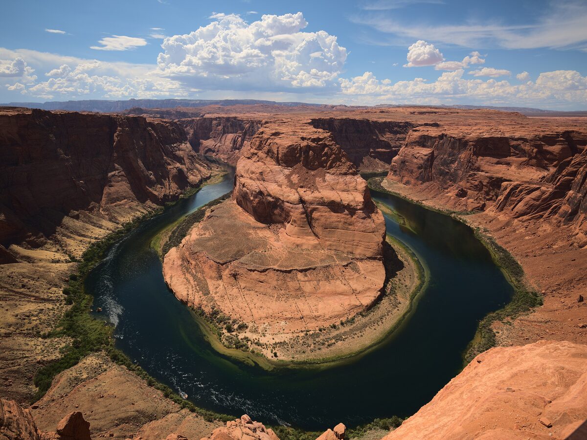 The Colorado River curving around Horseshoe Bend below red cliffs