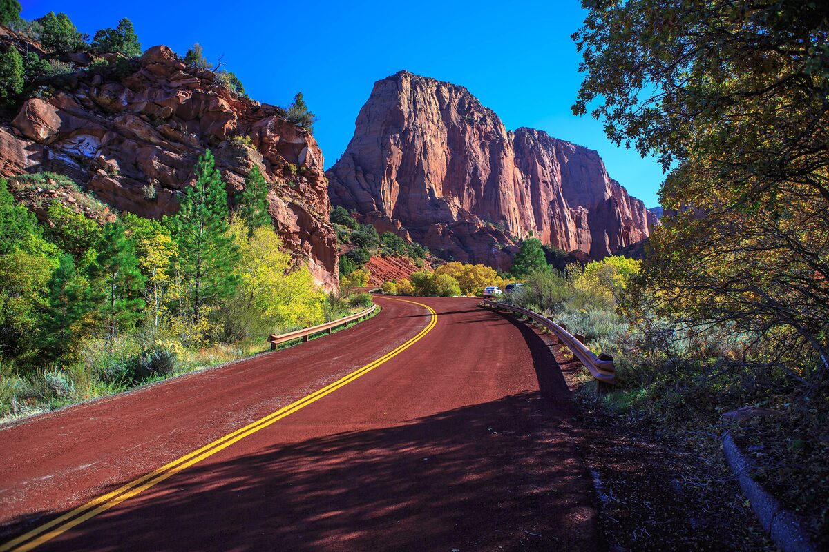 Scenic road beneath the red Kolob Canyons cliffs in autumn color