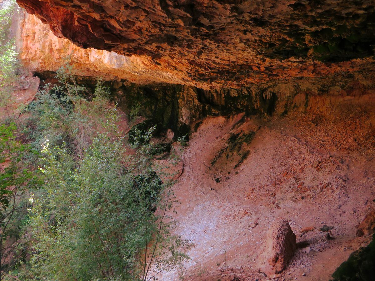 Overhanging red rock of the Mossy Cave seen from below