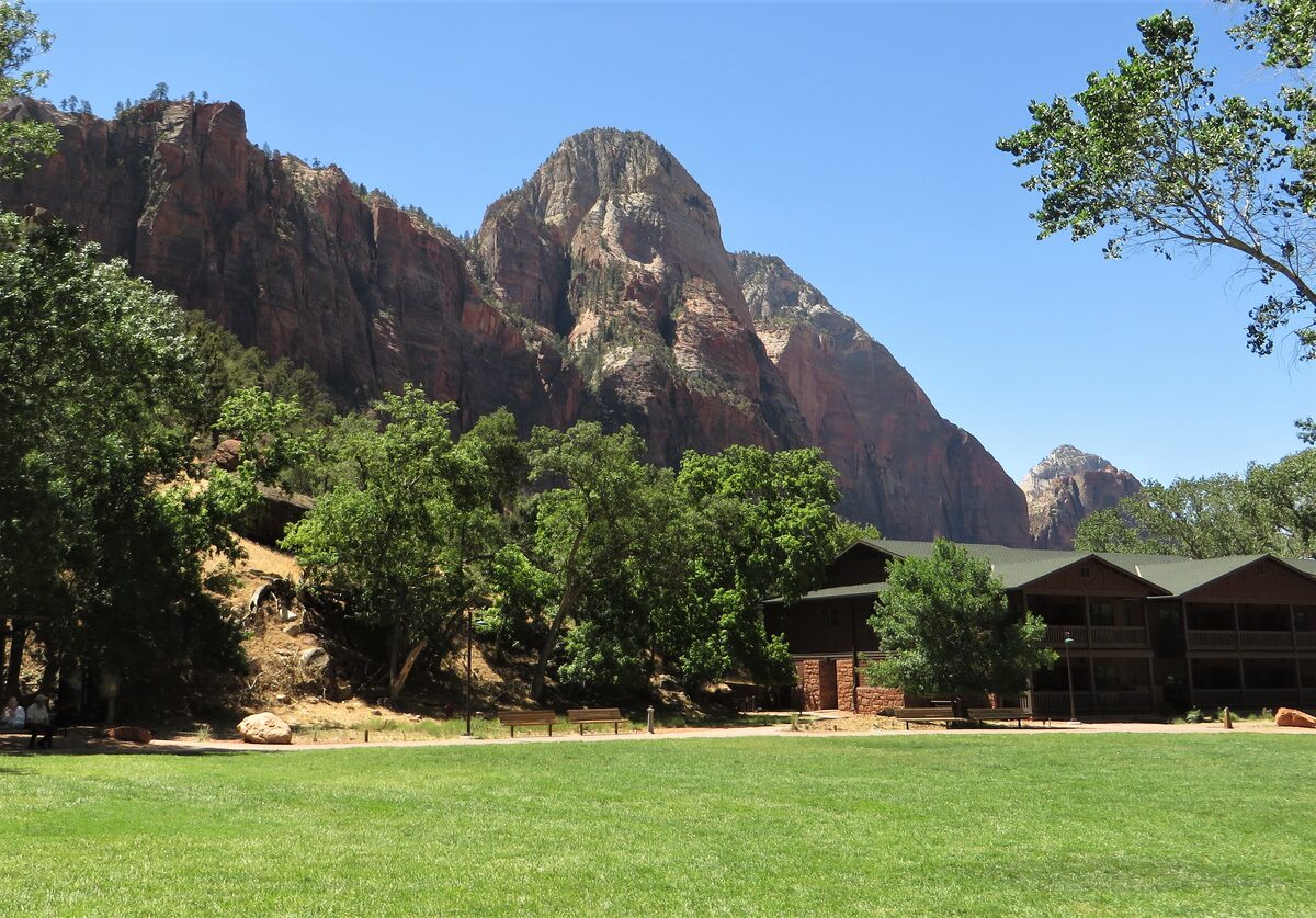 Zion Lodge cabins on a lawn below the red canyon walls
