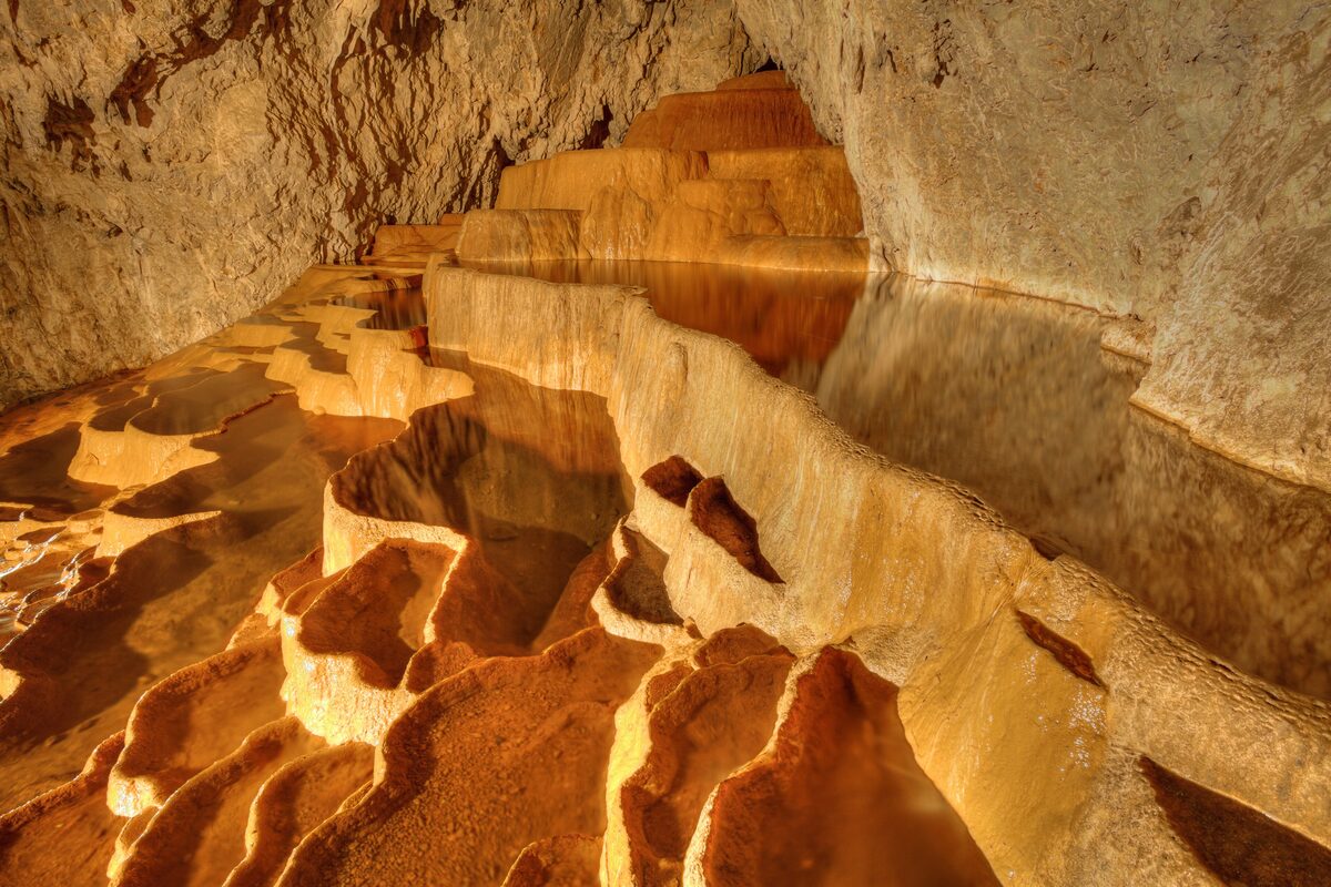 The travertine pools of Stopića cave, stepped basins of still water glowing gold under the cave lights.