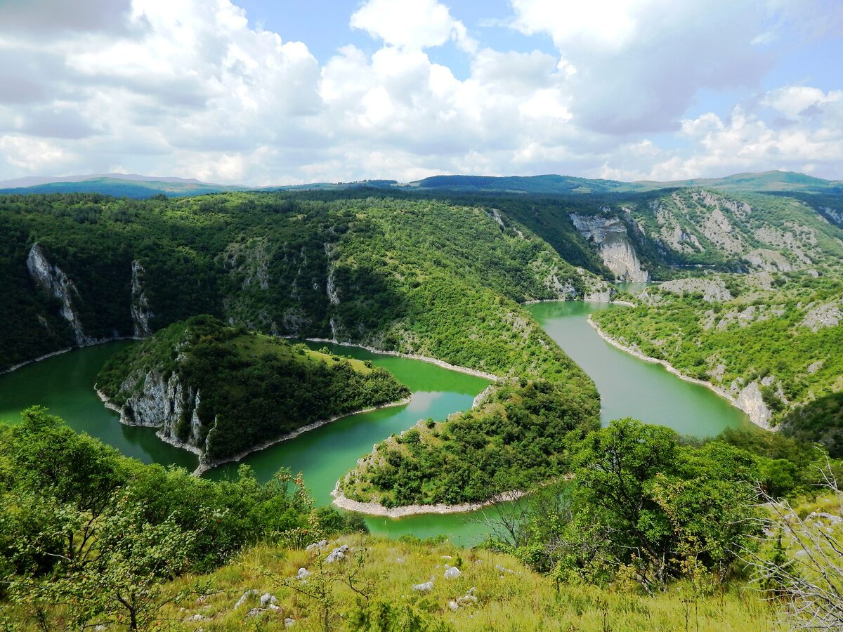 The green waters of the Uvac looping around wooded promontories between white limestone cliffs, seen from above.