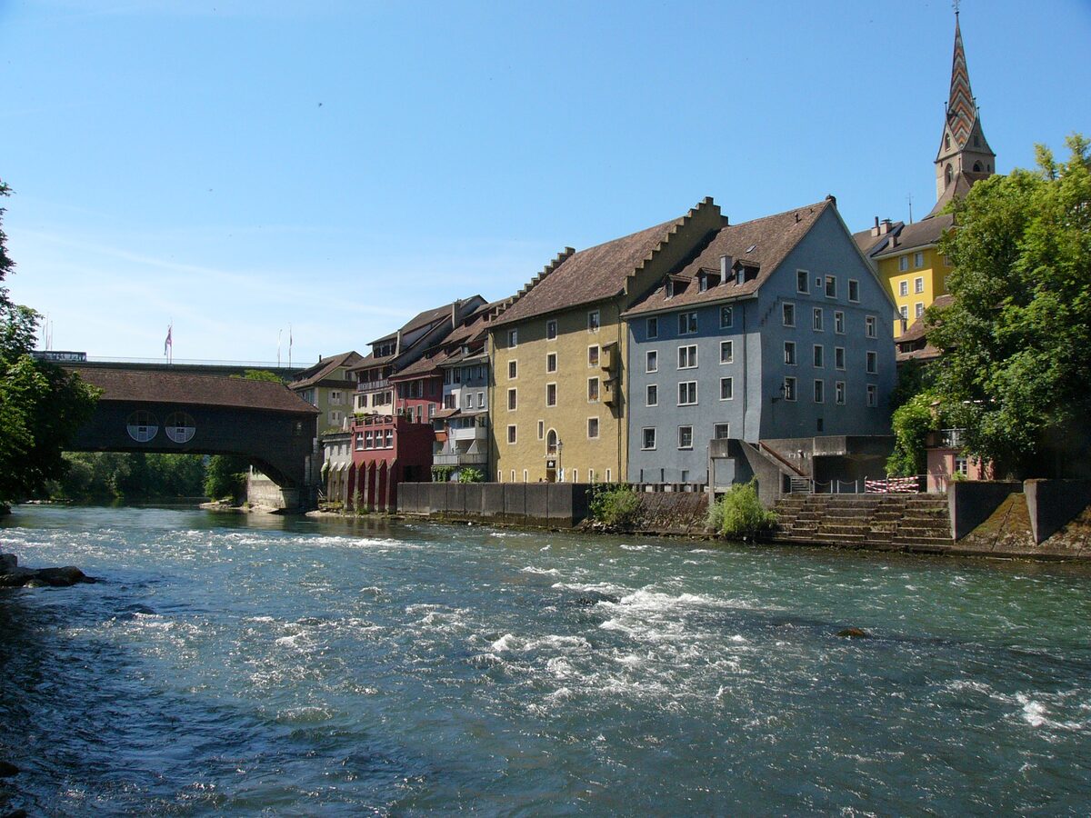 The Limmat running past the old town of Baden, with the covered wooden bridge and a church spire above the houses