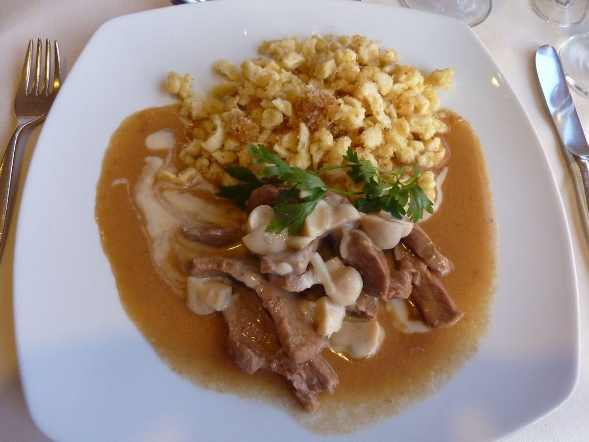 Sliced veal in a creamy mushroom sauce with Spätzle on a white plate