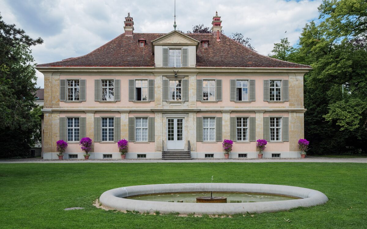 The garden front of the Lindengut museum in Winterthur, a pale mansion behind a lawn and a fountain