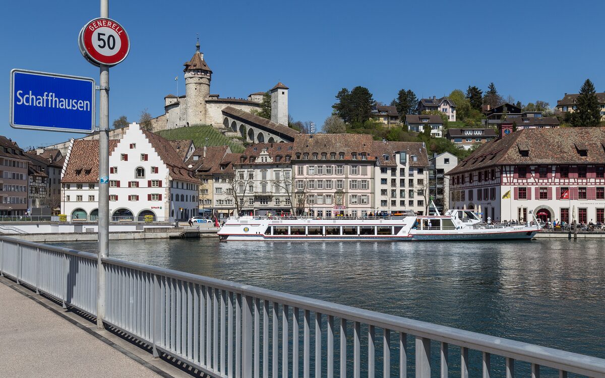 The Munot fortress on its hill above the Schaffhausen waterfront, with a white excursion boat moored on the Rhine