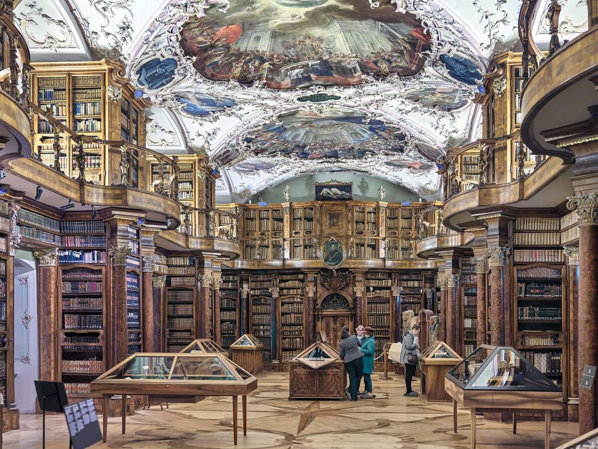 The baroque hall of the Abbey Library of St. Gall, with a painted ceiling, glass cases and tall wooden bookcases