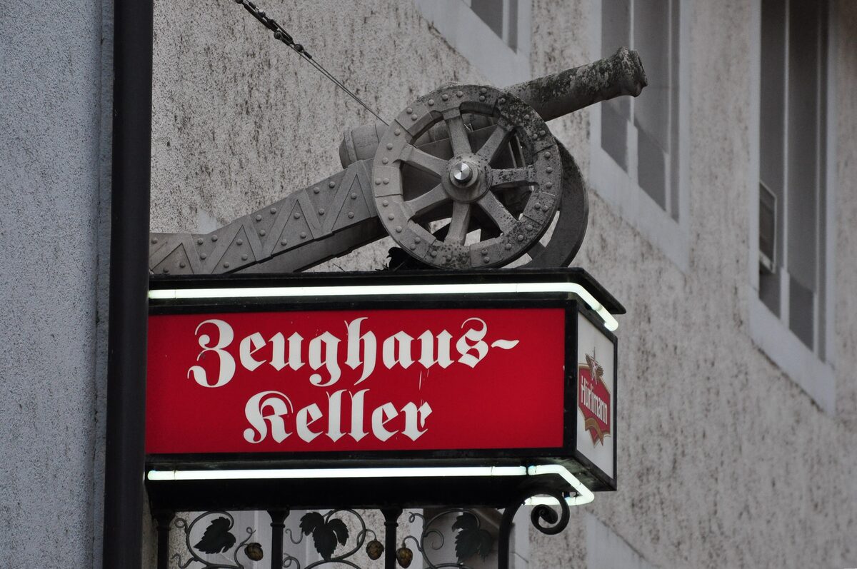 The red Zeughauskeller sign under an old iron cannon on a grey stone wall